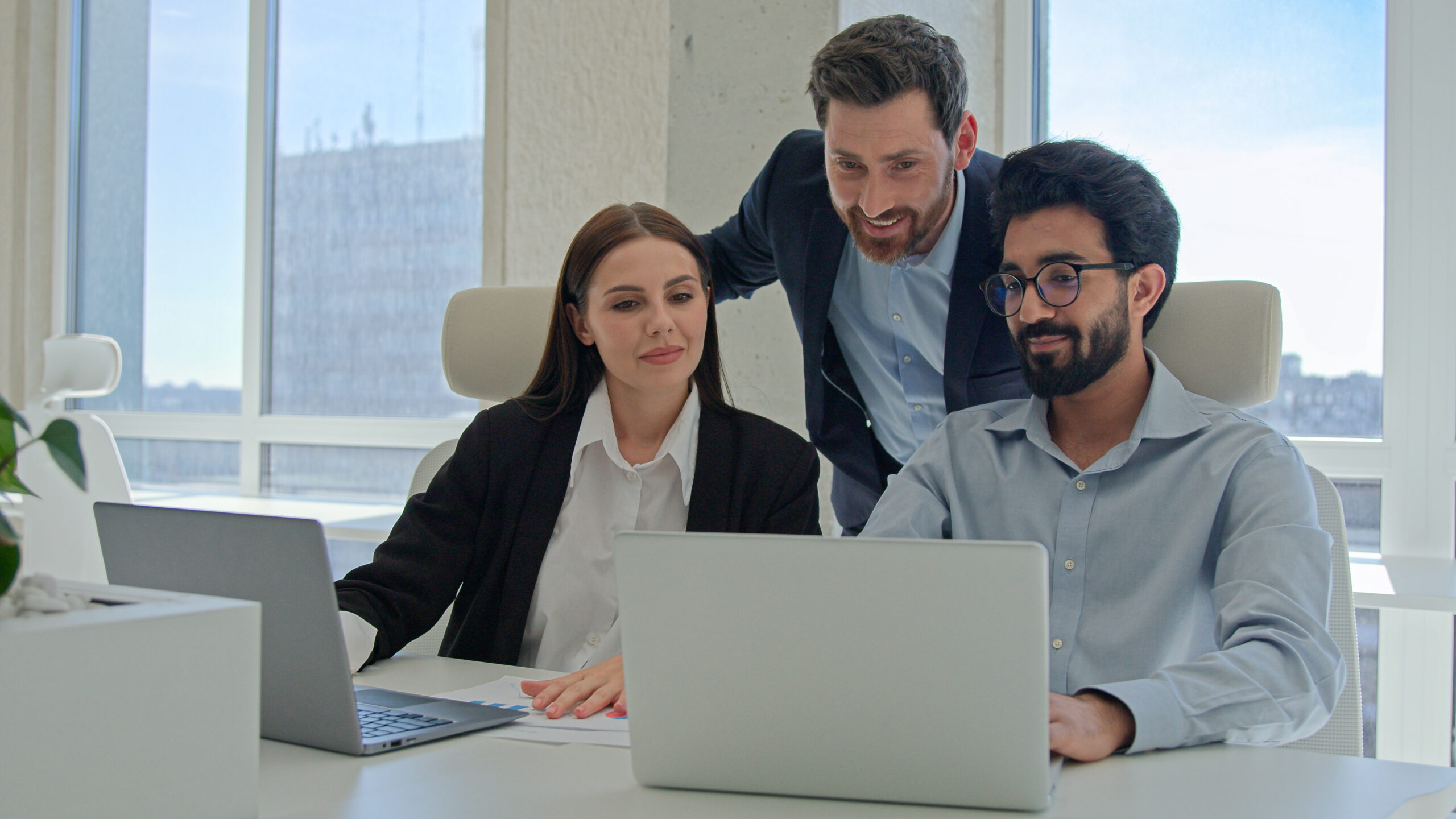 Three happy business people creative team coworkers smiling businessmen businesswoman working together at office company discussing project results mentor teaching office trainees teamwork cooperation. High quality 4k footage